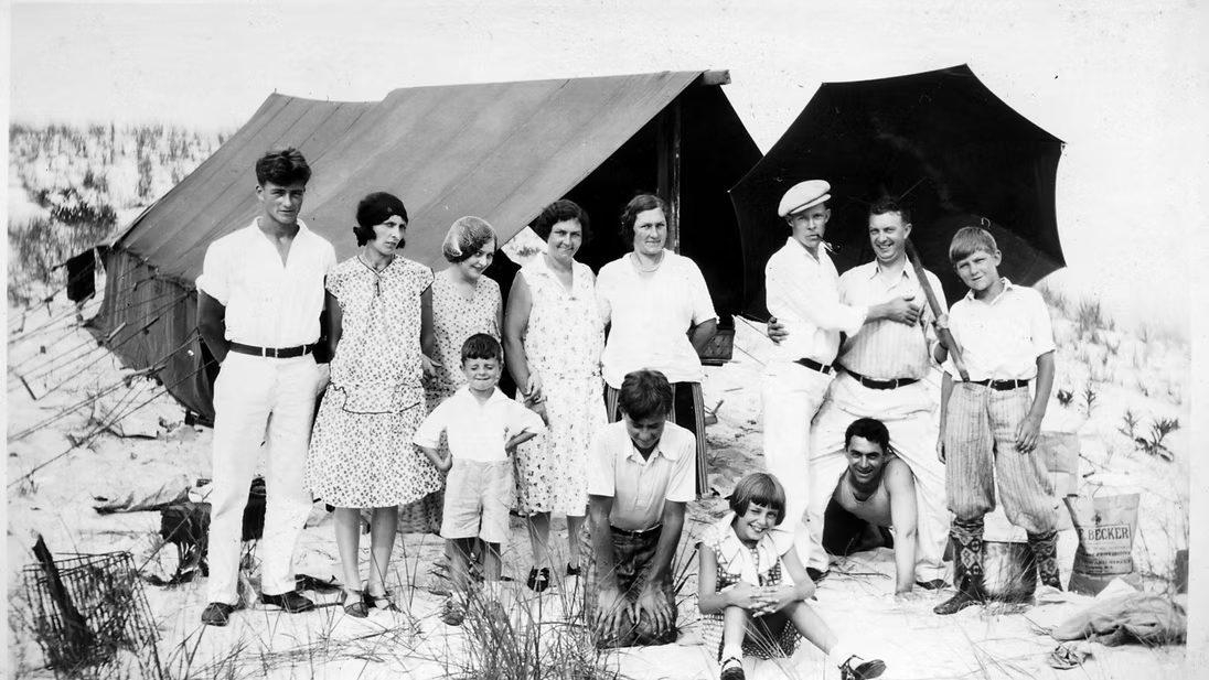 A group of early Harvey Cedars visitors gathered on the beach beside canvas tents